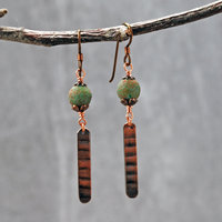 Earrings with green matte Czech glass on top, textured copper dangle below, hanging