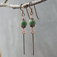 Earrings with green matte Czech glass on top, textured copper dangle below, hanging