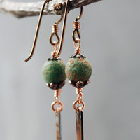 Earrings with green matte Czech glass on top, textured copper dangle below, close up of beads