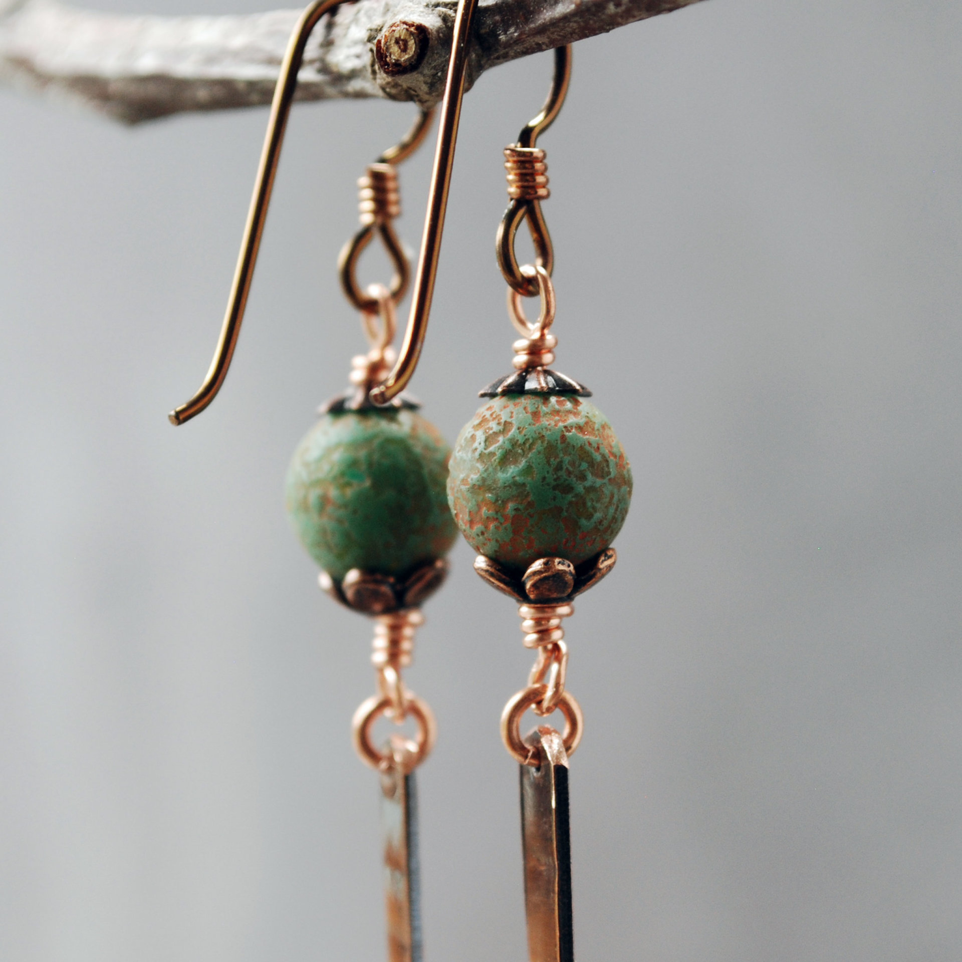 Earrings with green matte Czech glass on top, textured copper dangle below, close up of beads